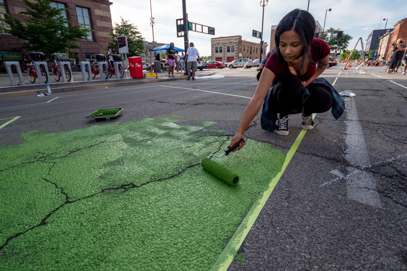 A Cincinnati artist begins to paint her design as 17 artists and their assistants begin to paint a Black Lives Matter mural on Plum St. at the footsteps of City Hall, Wednesday, June 17, 2020, in Cincinnati.